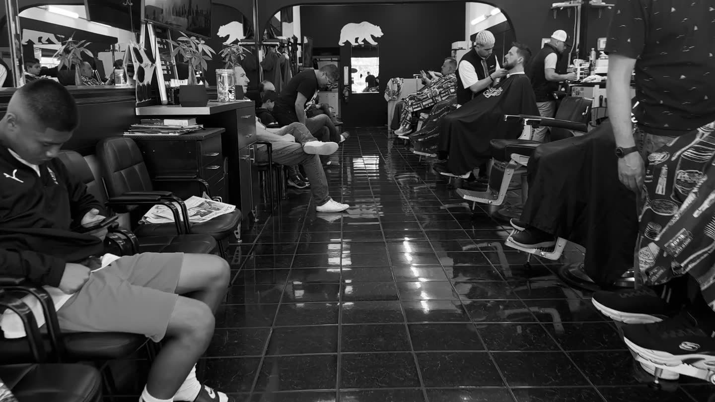 Interior of Arturo's Barbershop, with barbers cutting hair along a row of chairs